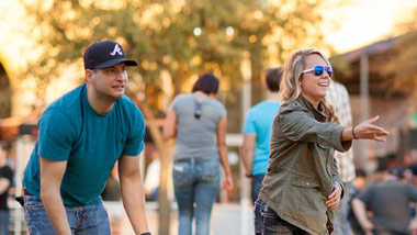 man and woman outside playing cornhole